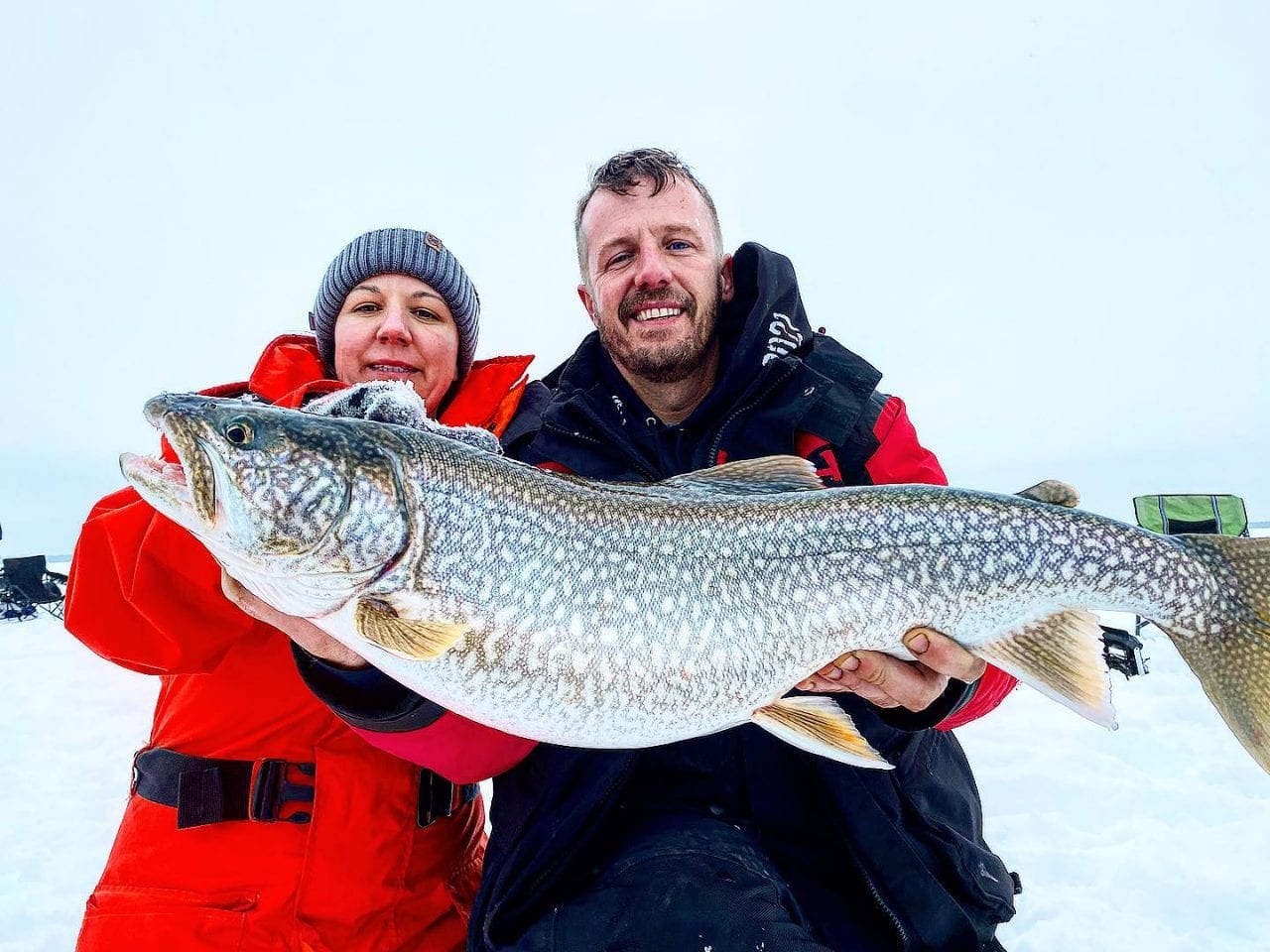 An accomplished Manitoba fishing guide holds up a catch while smiling with his student.
