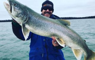 A happy angler holds up a massive lake trout caught while fishing outside of Flin Flon, Manitoba.