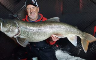 A dedicated ice fisherman hoists up a massive lake trout from Lake Athapapuskow outside of Flin Flon, Manitoba.