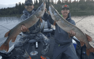 A duo of anglers holds up a pair of northern pike while fishing in Canada.