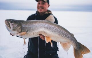 Ice Fishing Canada: An avid angler hoists a large lake trout for a picture.