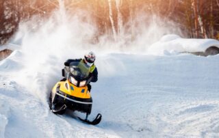 Manitoba Snowmobile Trails: An avid snowmobiler rides along a snow drift amid the snow covered trail.